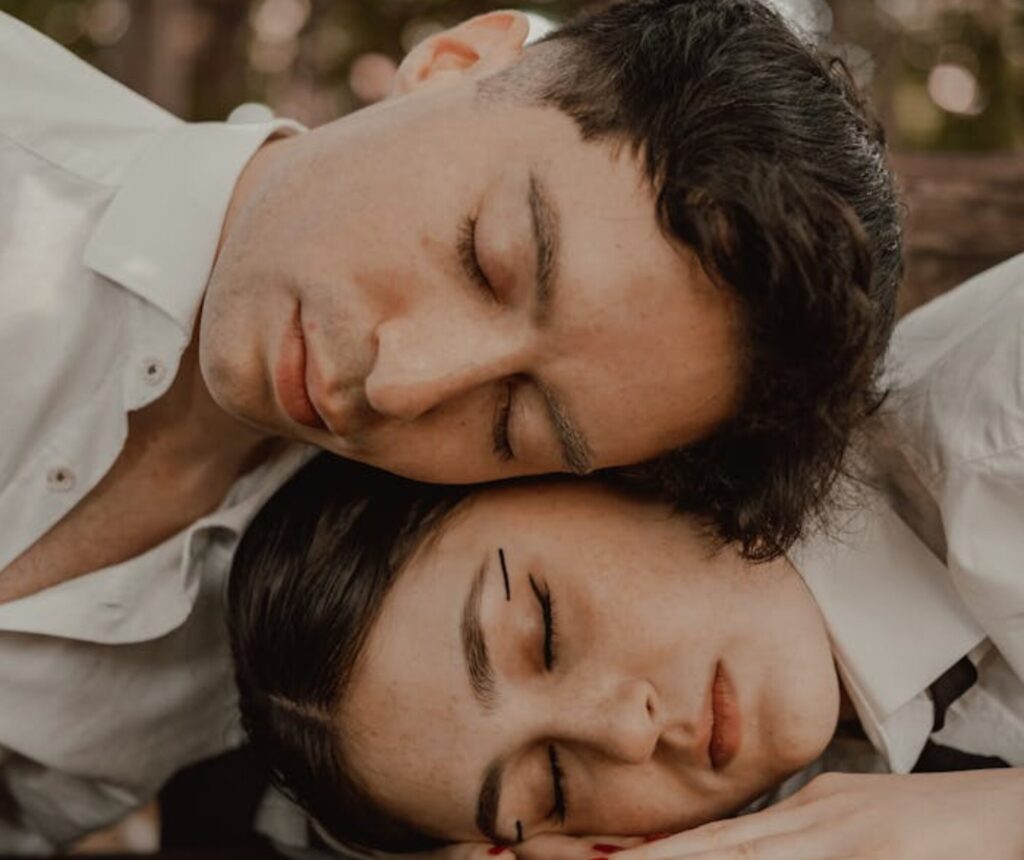 A couple sleeping on a bench in the woods